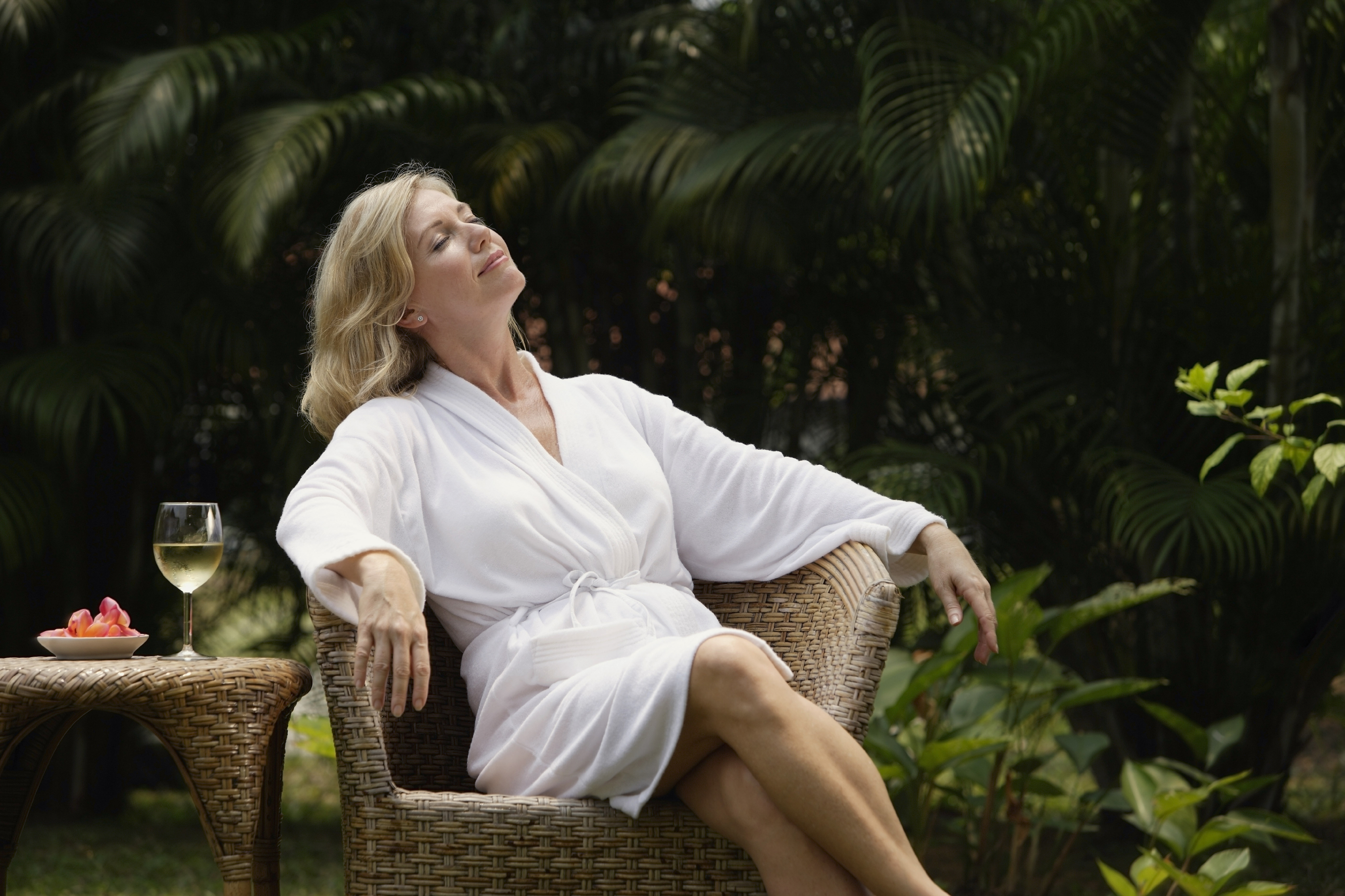 Woman sitting outside in robe, glass of wine